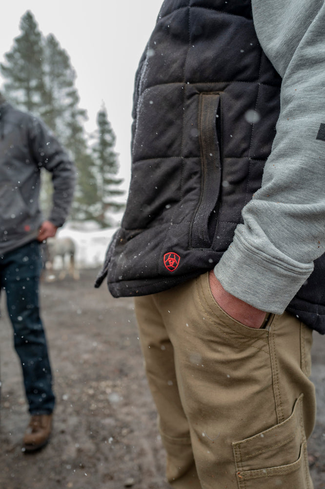 man has hands in pockets of cargo pants at a construction site in the winter