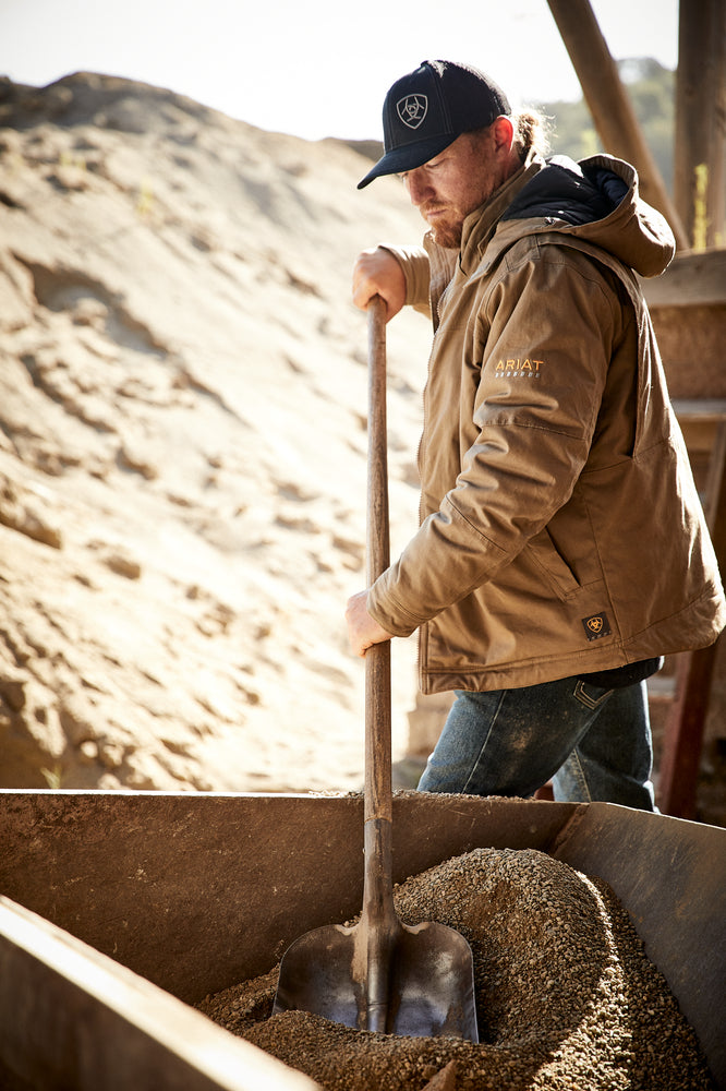 man in tough workwear turns cement at a construction site