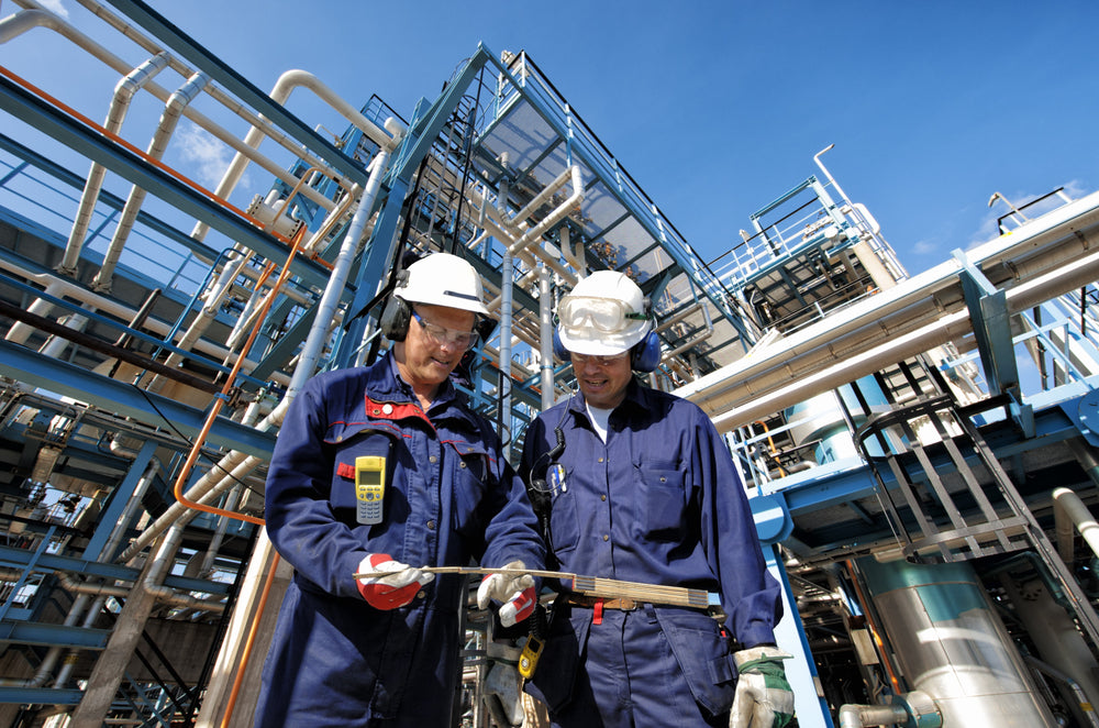 two construction workers in blue uniforms and hard hats stand in construction site